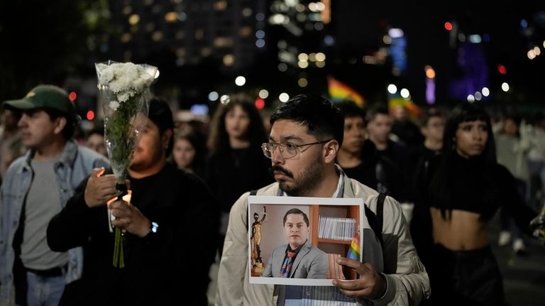 A demonstrator holds a picture of Aguascalientes state electoral court...