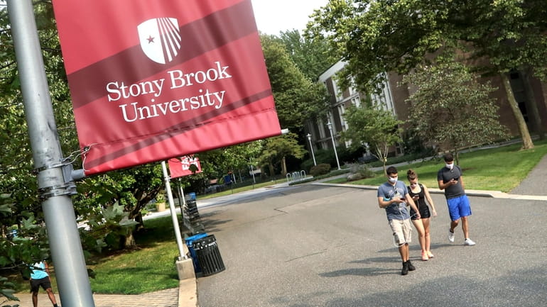 Students walk through the Stony Brook University campus in August...