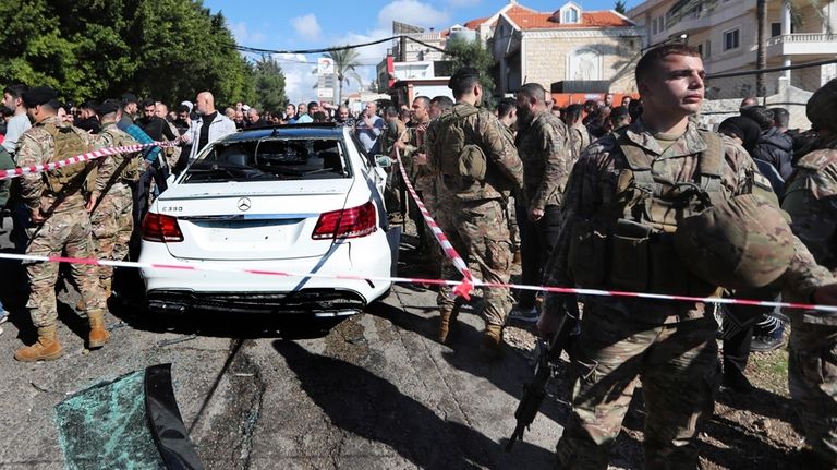 Lebanese army soldiers gather around a damaged car near the...