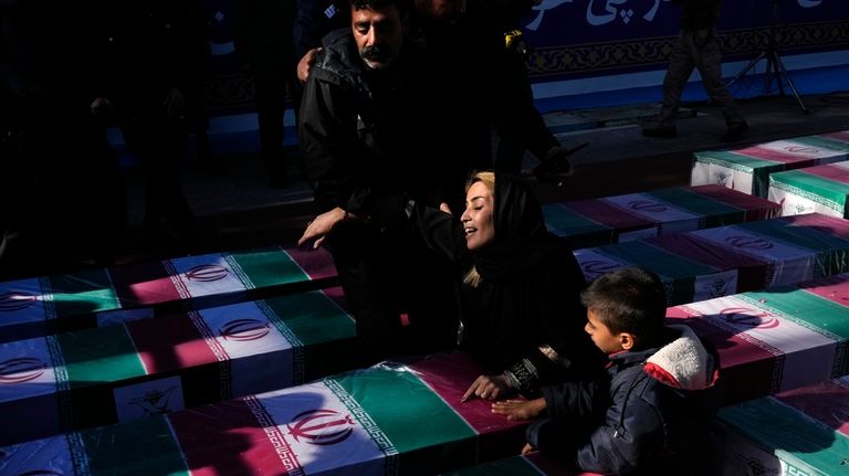 A woman mourns over the flag-draped coffin of her loved...