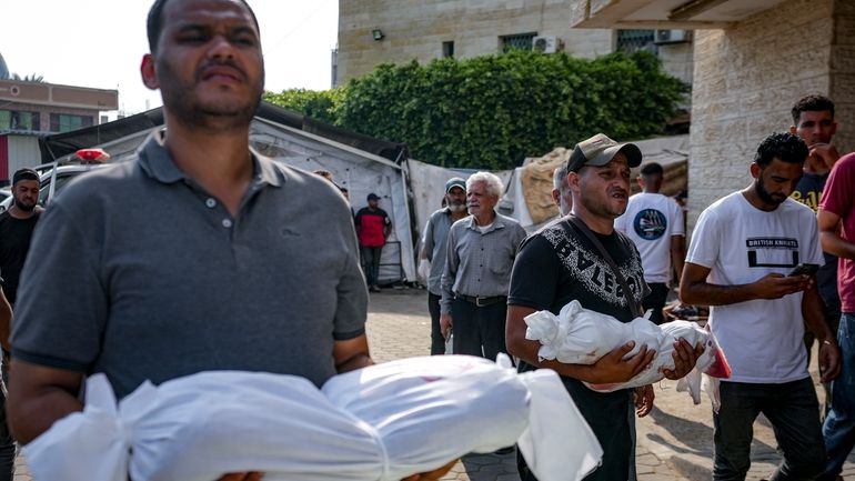 Palestinians hold the bodies of their relatives killed in the...