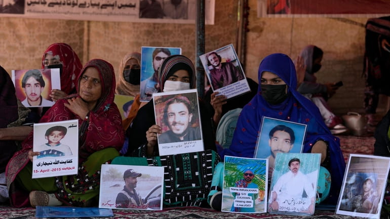 Baloch activists hold portraits of their missing family members during...
