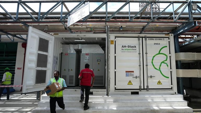 A worker walks in front of the 500-kilowatt battery energy...