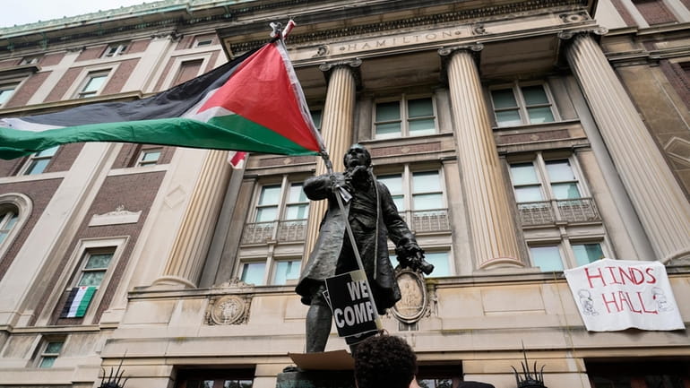 A student protester parades a Palestinian flag outside the entrance...