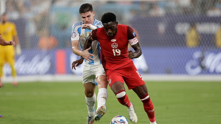 Argentina's Julian Alvarez, left, and Canada's Alphonso Davies vie for...