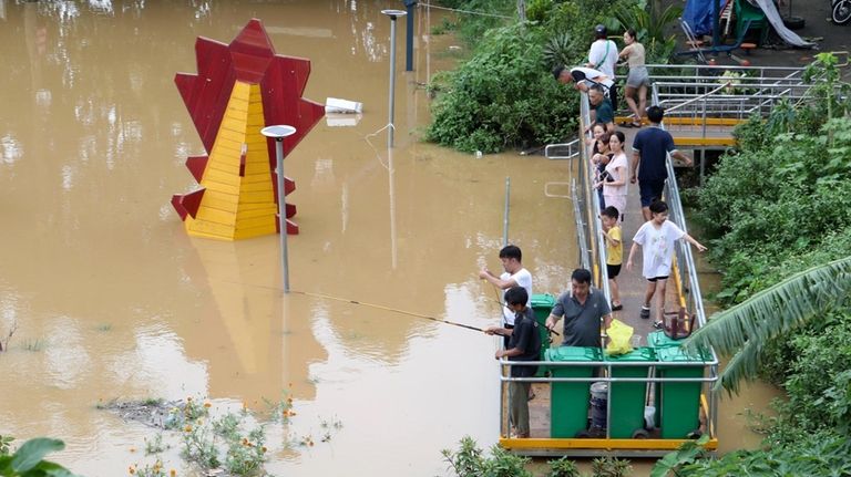 People fish next to a submerged playground due to flood...