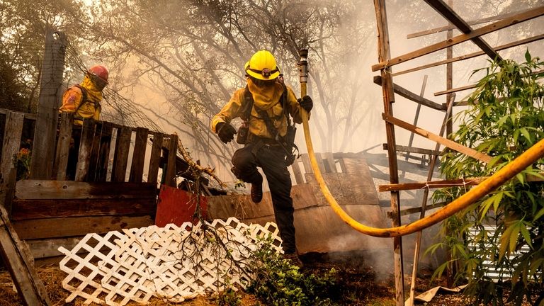 Firefighter Christian Moorhouse jumps over a fence while battling the...