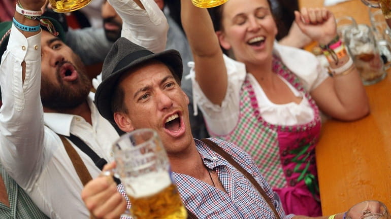 Visitors hold up one-liter glasses of beer to kick off...