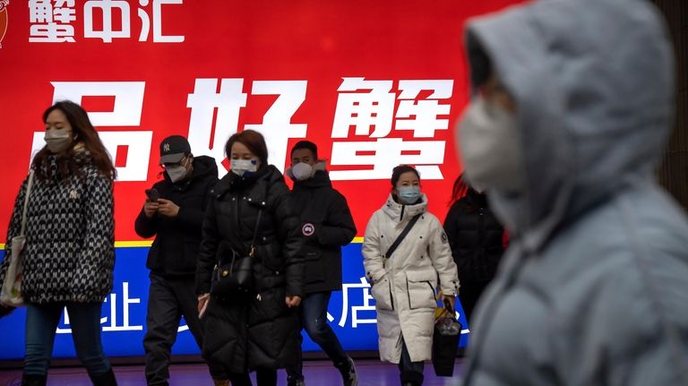 Commuters wearing face masks walk out of a subway station...