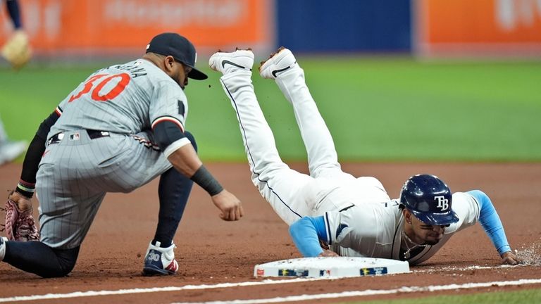 Tampa Bay Rays' Christopher Morel dives back safely to first...