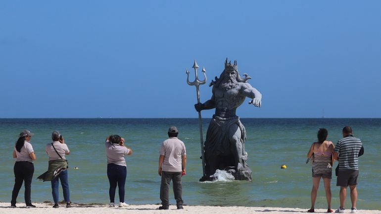 Tourists take pictures of Poseidon sculpture before the arrival of...