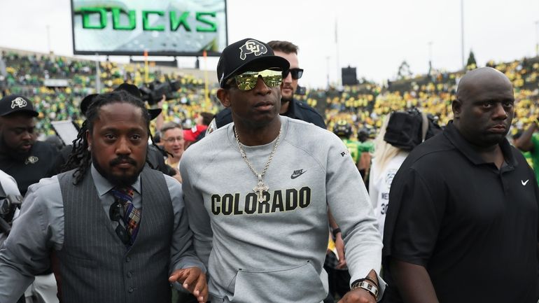 Colorado head coach Deion Sanders, center, exits the field following...