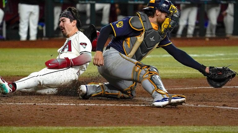 Arizona Diamondbacks' Corbin Carroll, left, slides into home behind Milwaukee...