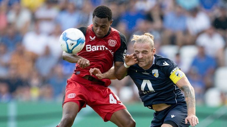 Leverkusen's Jeanuel Belocian, left, and Jena's Nils Butzen challenge for...