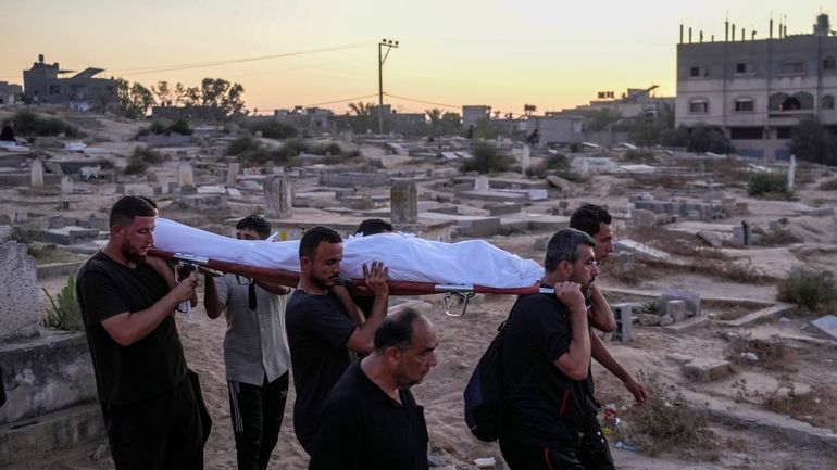 Palestinian mourners carry their loved one for burial at the...