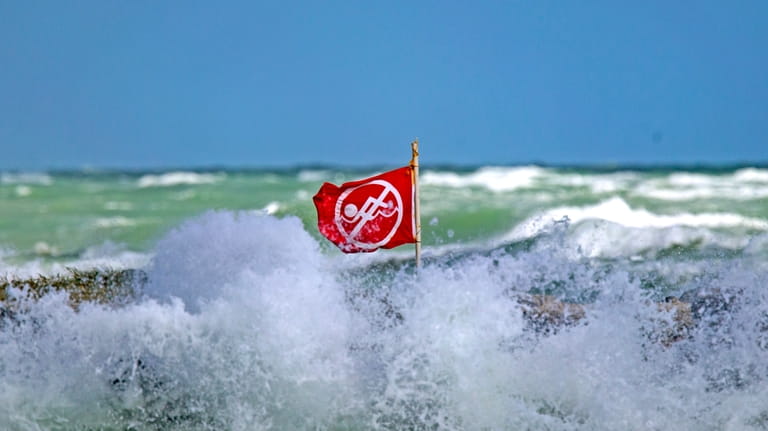 A no swimming flag is visible as waves crash against...