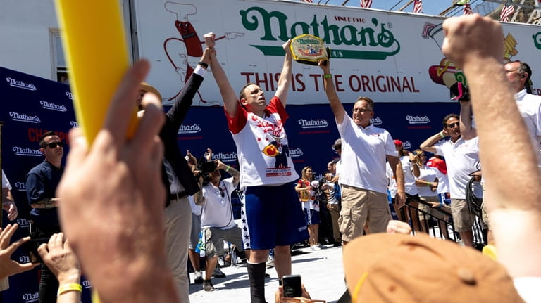 Joey Chestnut, center left, celebrates winning the Nathan's Famous Fourth...