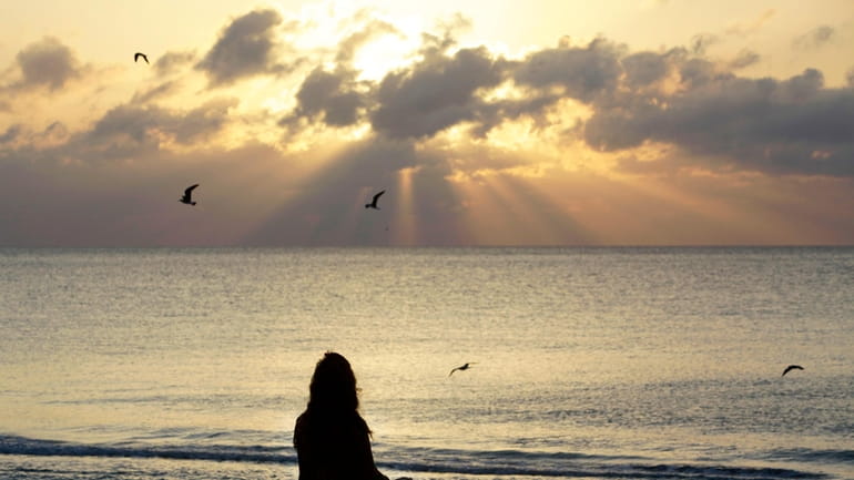 A woman meditates on the beach in Miami Beach, Fla.,...