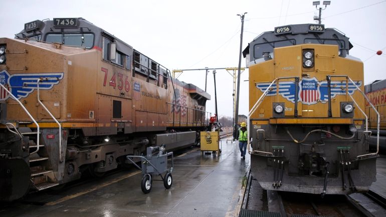 A Union Pacific worker walks between two locomotives being serviced...