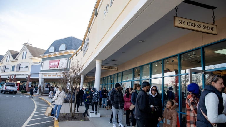Shoppers wait to enter stores at Tanger Outlets in Riverhead...