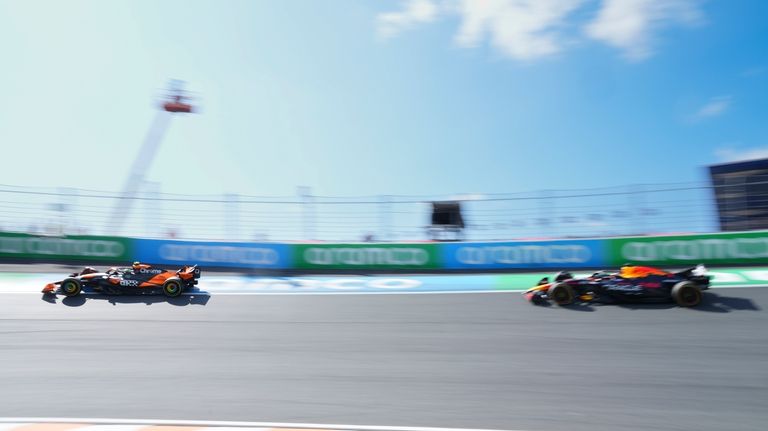 McLaren driver Lando Norris of Britain, left, steers his car...