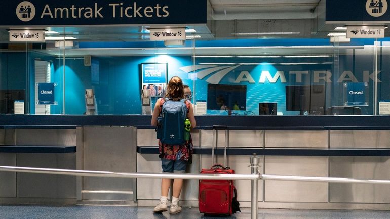 A rider speaks to an Amtrak worker at Penn Station in...