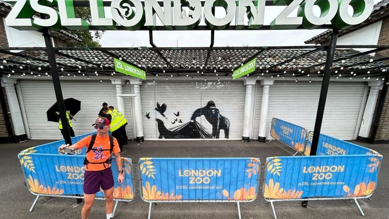 A man snaps a selfie with a mural by the...