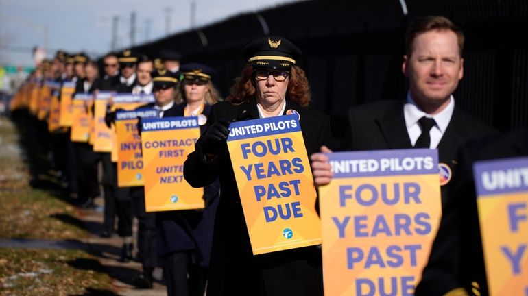 United Airlines pilots as well as other supporters walk an...