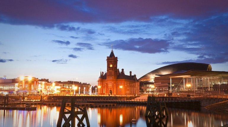 The night illuminations off Cardiff Bay dance around the Pierhead...