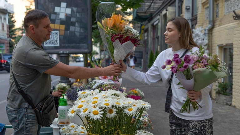 A woman buys bouquets of flowers at a street flower...
