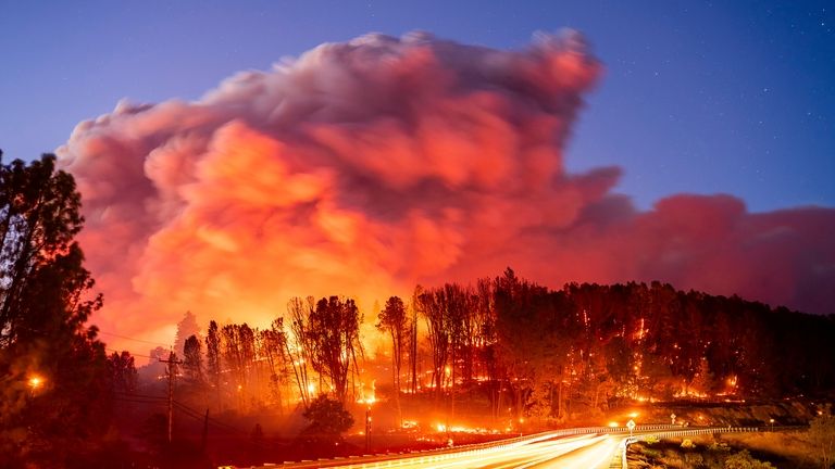 Seen in a long exposure photograph, the Park Fire burns...