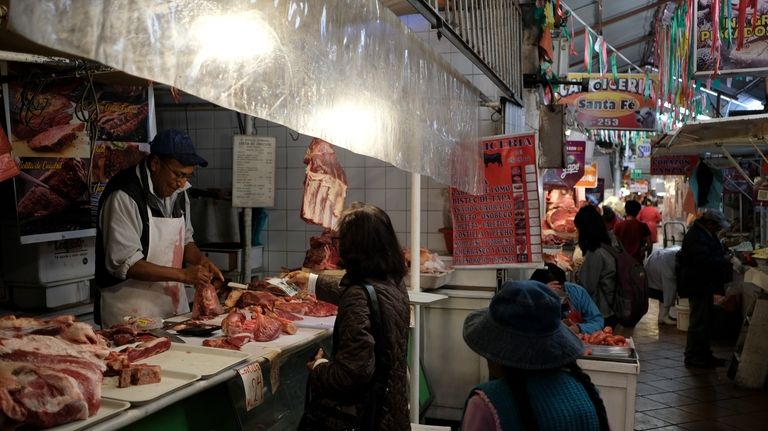 A butcher attends to a customer at a market in...