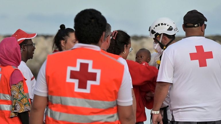 A baby is carried by members of the Red Cross...