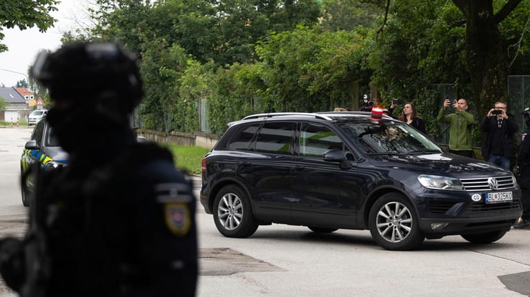 Policemen guard the area as convoy brings the suspect, in...