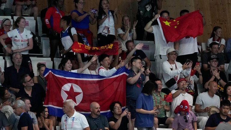 North Korean and China supporters hold flags during the women's...