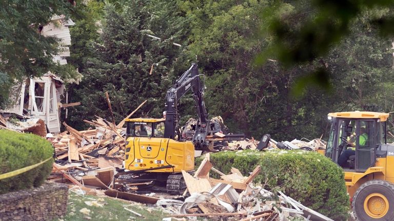 Crew workers remove debris after a house exploded in Bel...