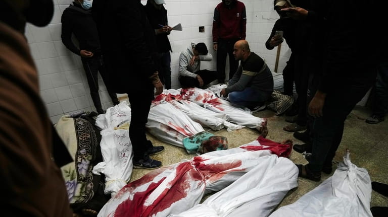 Relatives stand around the bodies of Palestinians killed in the...