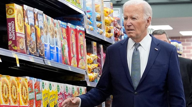 President Joe Biden walks past boxes of cereal in an...