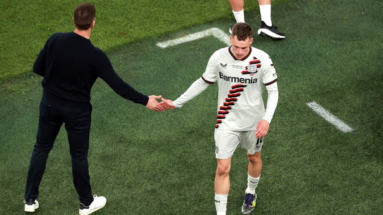 Leverkusen's Florian Wirtz, right, greets Leverkusen's head coach Xabi Alonso,...
