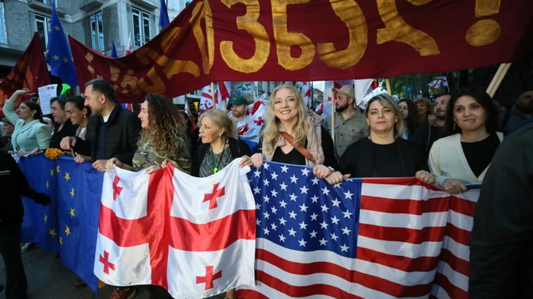Demonstrators with Georgian national, EU and U.S. flags rally during...