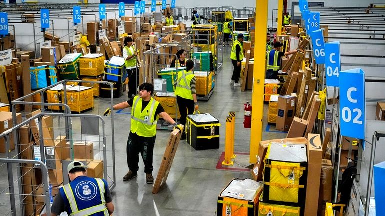 Amazon employees load packages on carts before being put on...