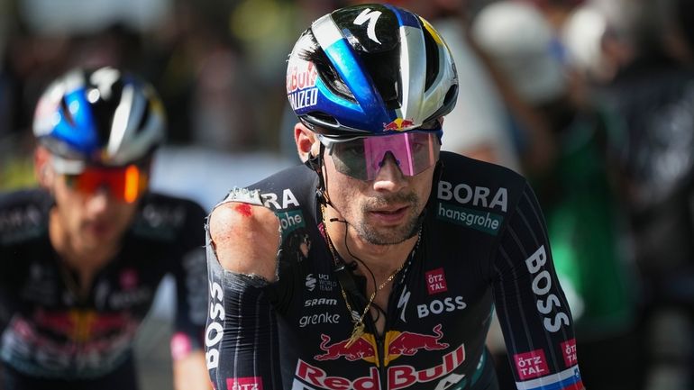 Slovenia's Primoz Roglic crosses the finish line with a shoulder...