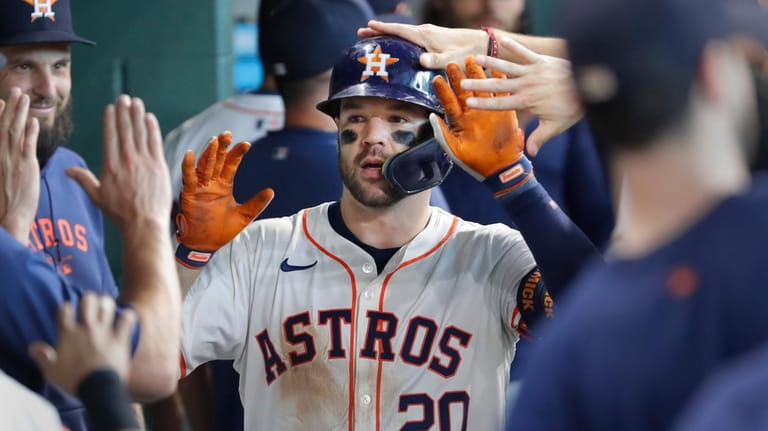 Houston Astros' Chas McCormick (20) collects high-fives in the dugout...