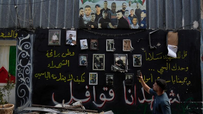 A man takes a picture of a wall displaying photos...