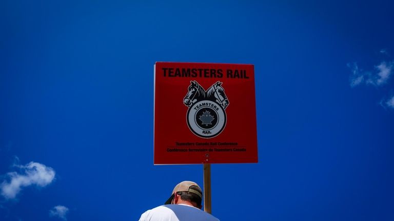 A picketer carries a Teamsters Rail placard at a Canadian...