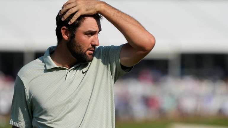 Scottie Scheffler walks off the 18th green after the final...