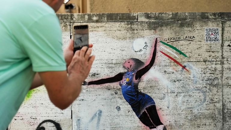 A man takes a picture at Laika's street-art celebration of...