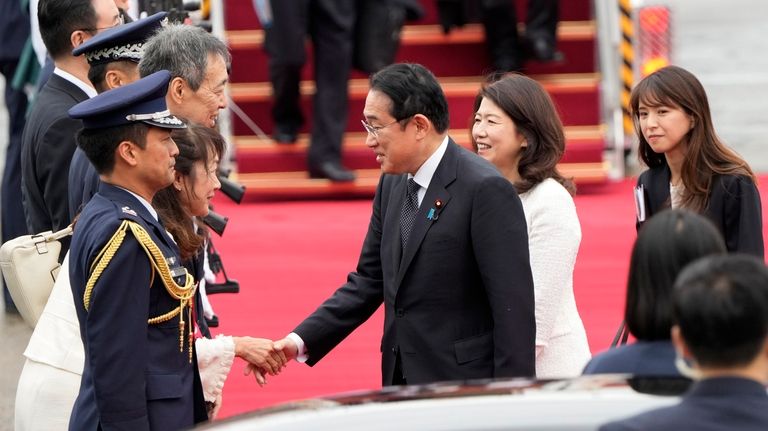 Japanese Prime Minister Fumio Kishida, center left, is greeted as...