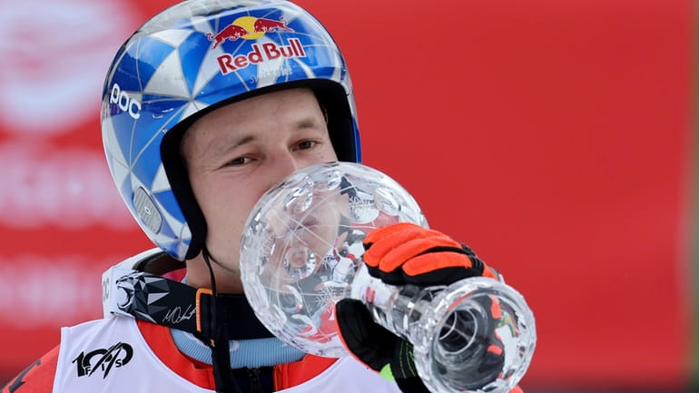 Switzerland's Marco Odermatt kisses the trophy of the alpine ski,...