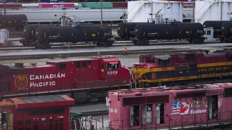 A worker walks past tanker cars and locomotives at the...